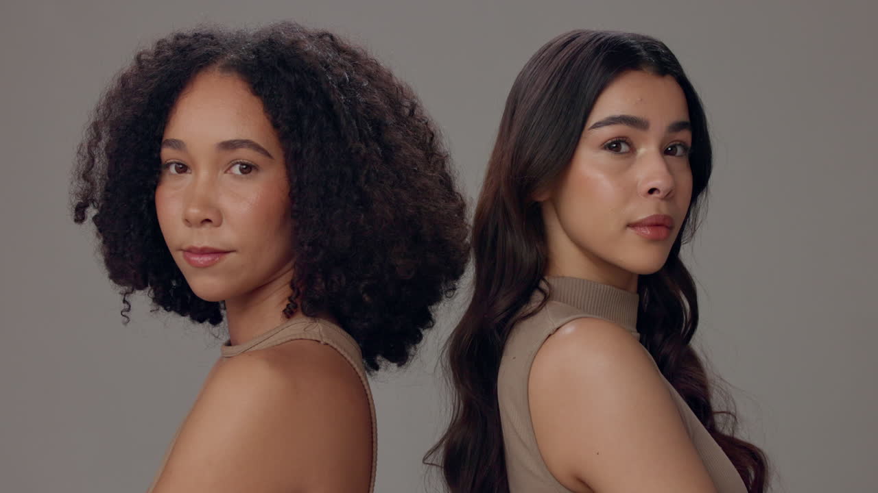 두 명의 웃는 친구들이 스튜디오에서 함께 포즈를 취합니다.