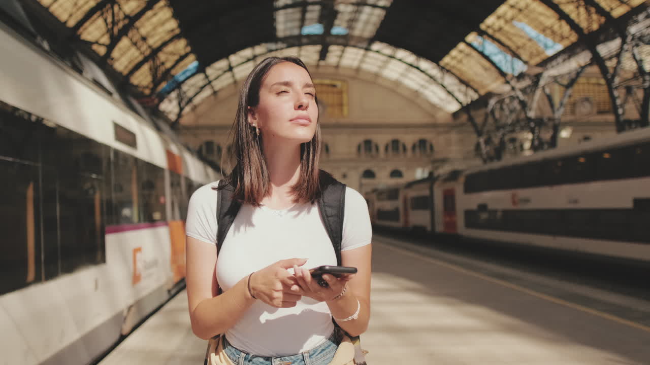 Giovane donna che usa lo smartphone mentre aspetta alla stazione ferroviaria