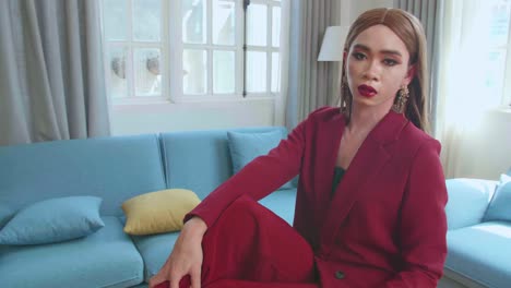 young fashion transgender woman wearing red clothes sitting on table and posing in home