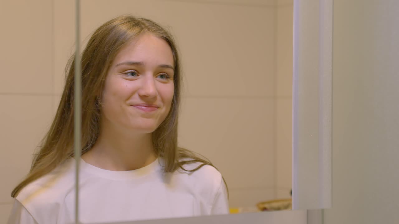 Young woman with brown hair looking in the bathroom mirror, in Slow Motion