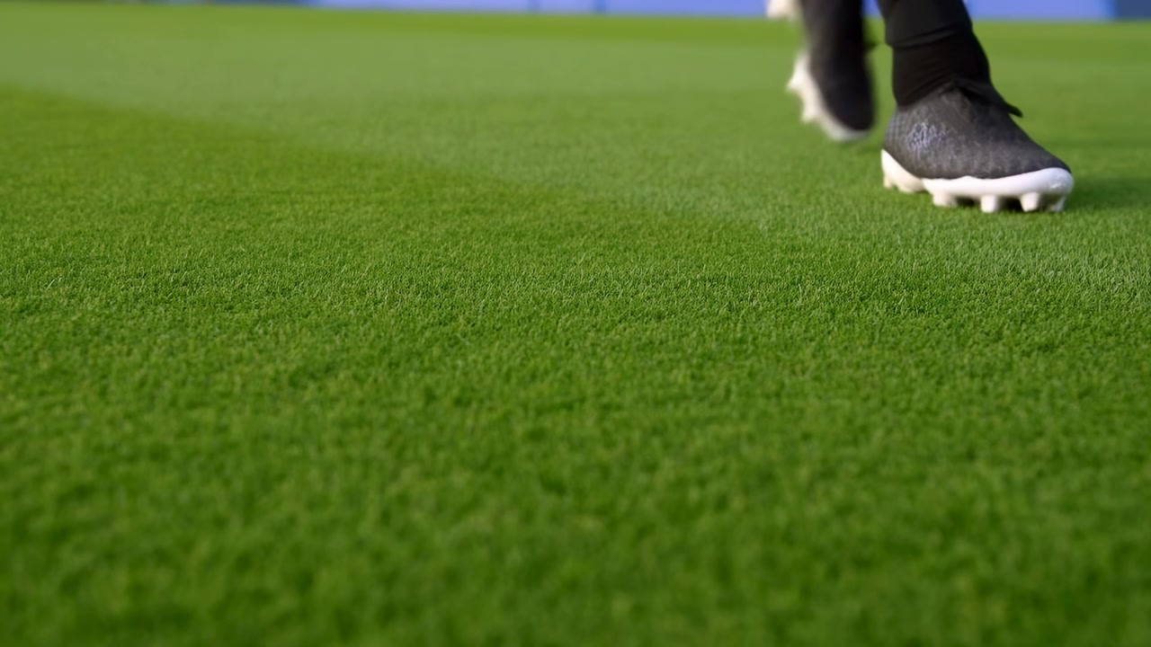 Un golfista concentrado y atlético golpea con un palo en un campo de hierba, capturando el movimiento y la precisión del swing desde una perspectiva de primer plano a ras de suelo con una pelota de golf verde a la vista.