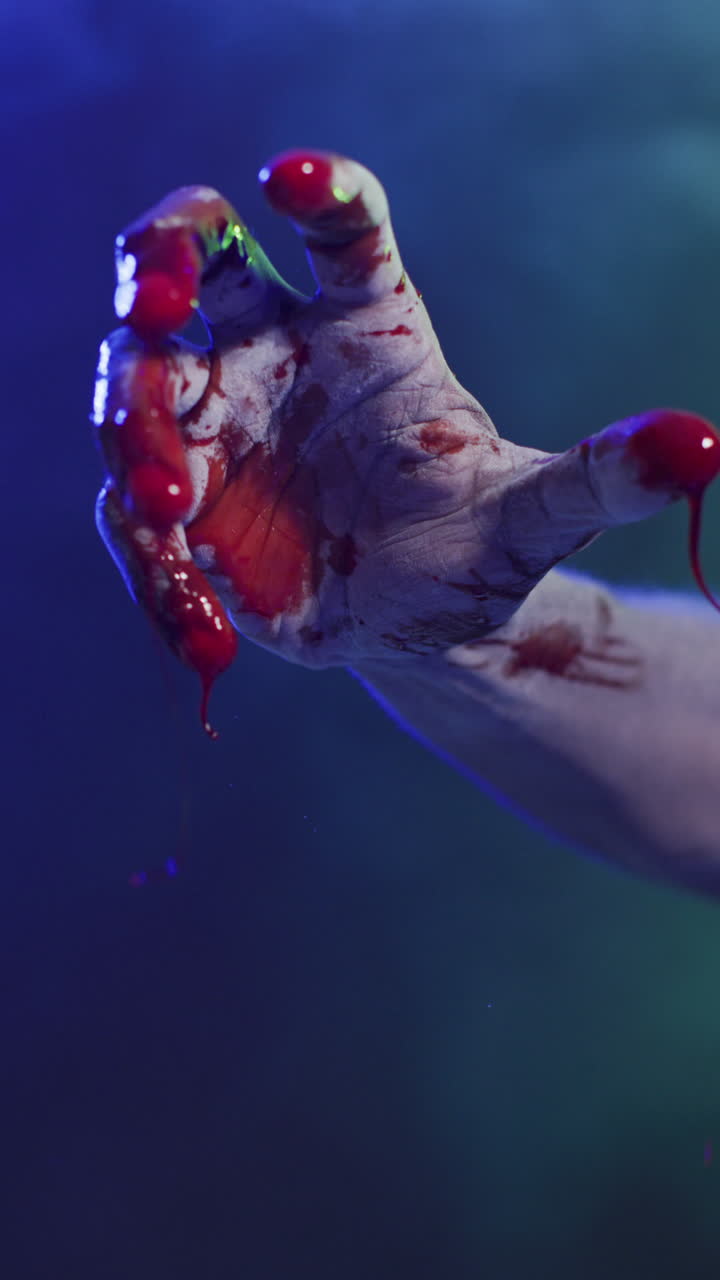 video vertical de manos cubiertas de sangre moviéndose sobre un fondo negro