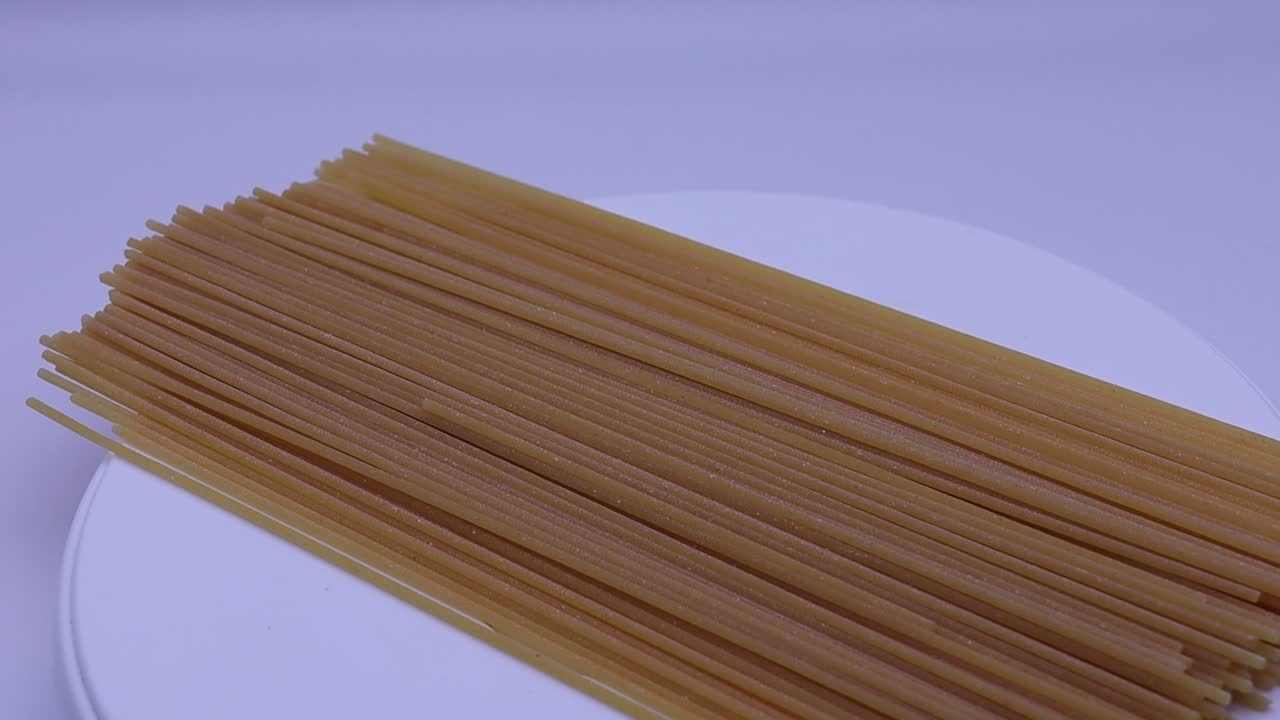 Pasta di spaghetti cruda su sfondo bianco brillante, pronta per essere cucinata
