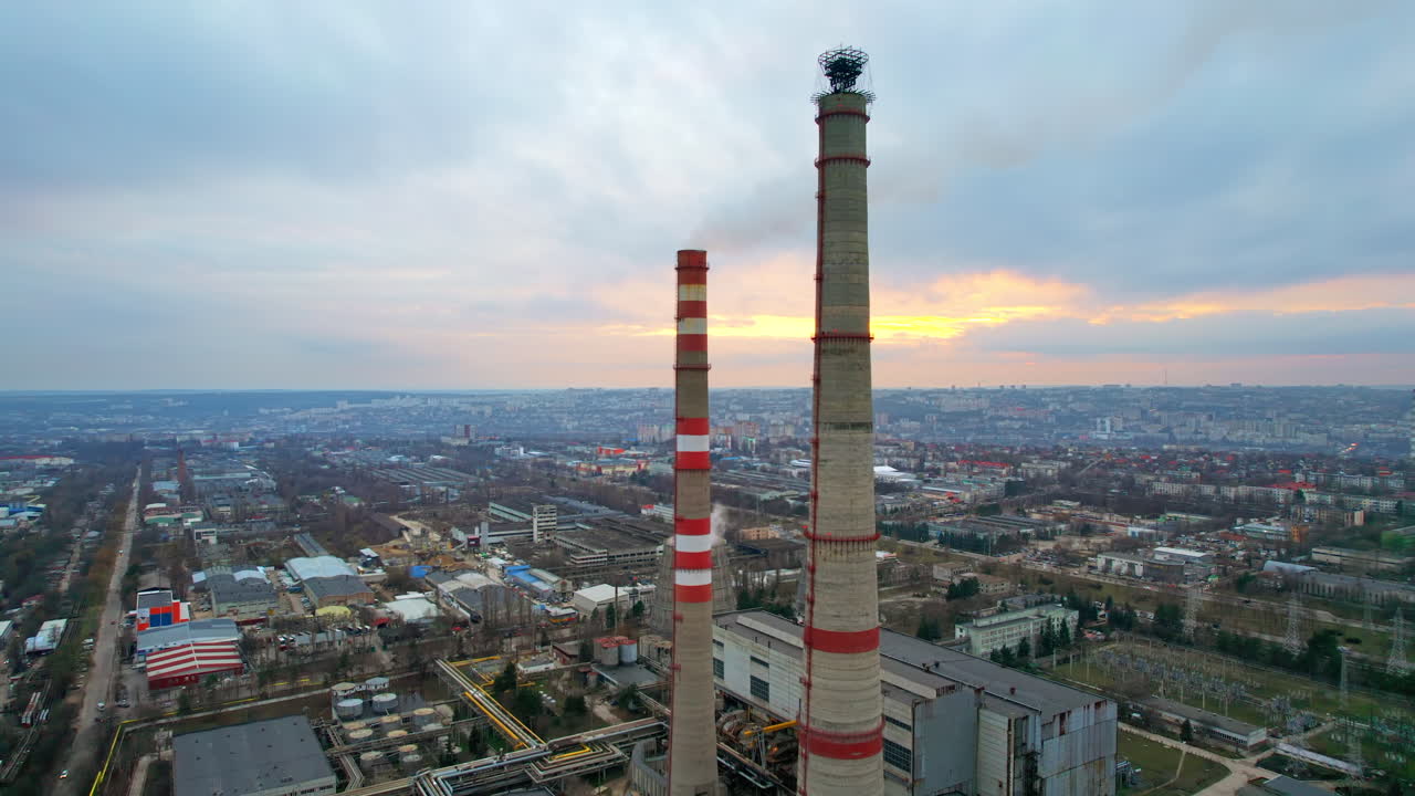 Aerial drone view of thermal power plant in Chisinau at cloudy weather, Moldova. View of pipes with felling steam, cityscape, sunset