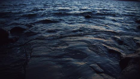 waves crashing at the rocks on the beach at sundown