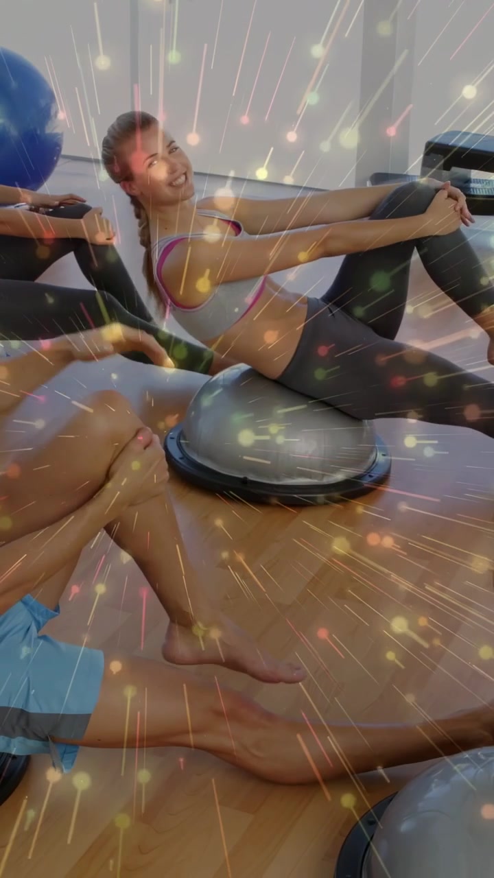 Vertical video: On instructor cue woman rocking BOSU holding knees for fitness, sparkles over group