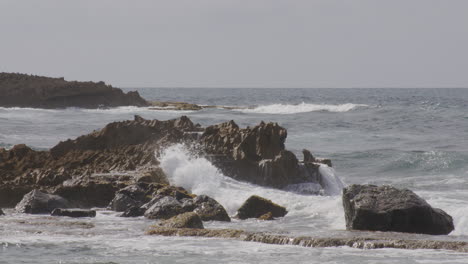 waves hitting and splashing into the rocks seaside of the beach on a cloudy day