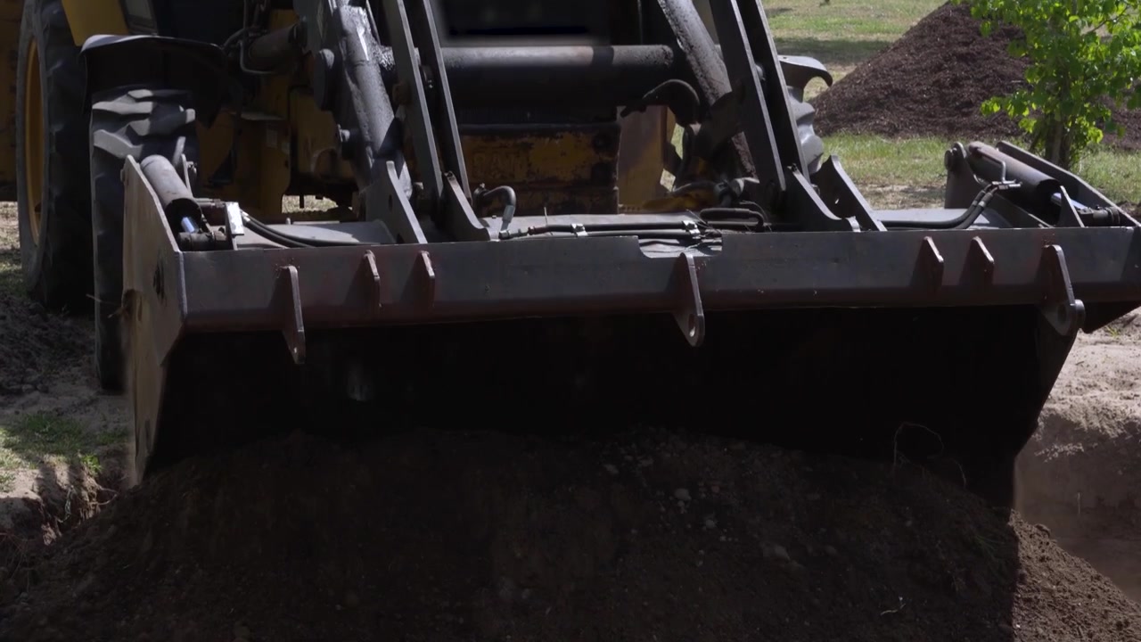 Bulldozer bucket unloading fresh topsoil for a rain garden construction project