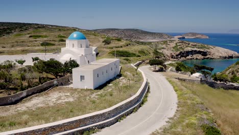 iglesia de la cima de la colina cámara aérea hacia adelante, con el mar azul y las colinas verdes más allá, amorgos, grecia