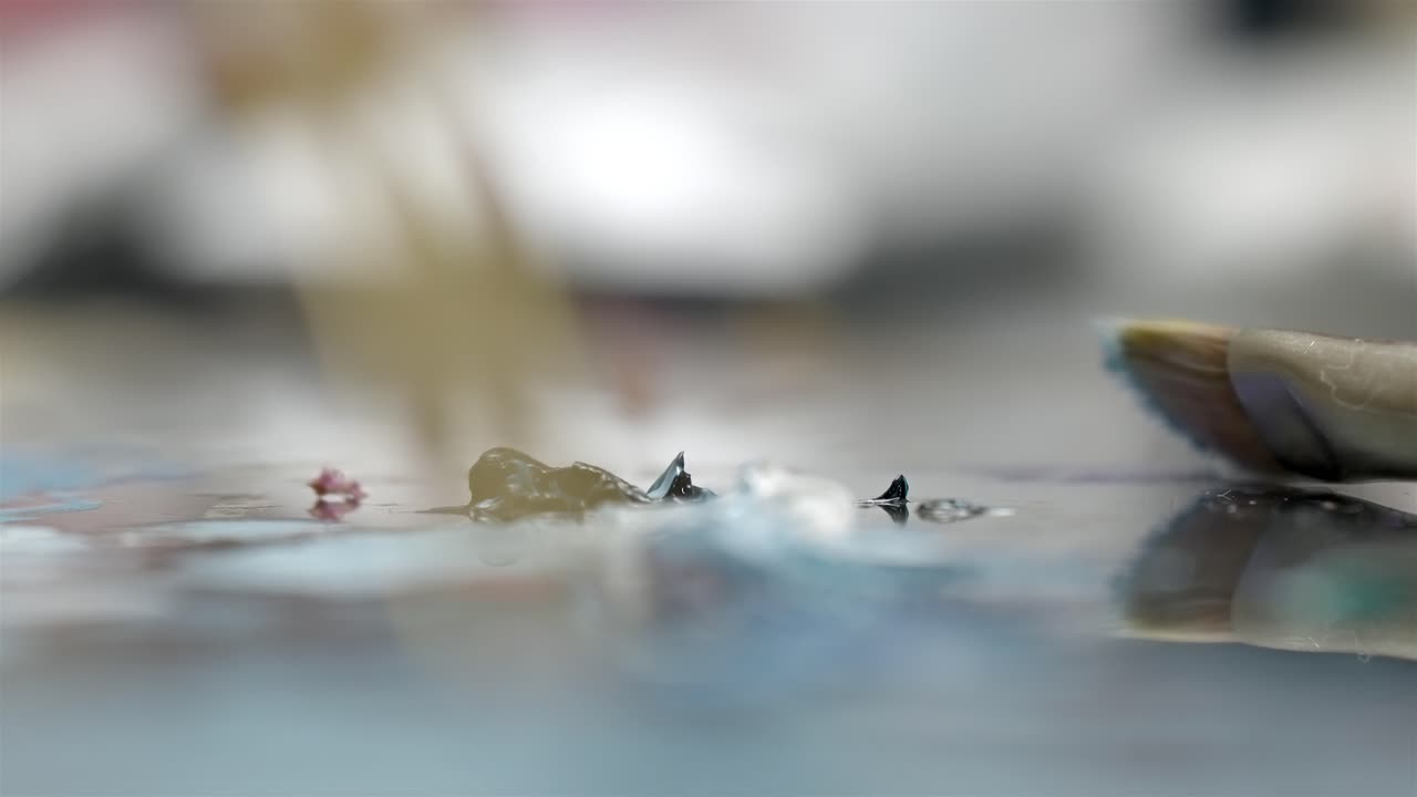 Goccia di pittura a olio bagnata su tavolozza di miscelazione con messa a fuoco macro estrema.