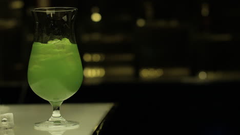 agregando unos cubitos de hielo en un vaso de margarita verde