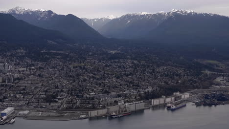 Aerial-View-Of-North-Shore-In-Vancouver-Harbour-With-Snowy-Mountains-In-Background