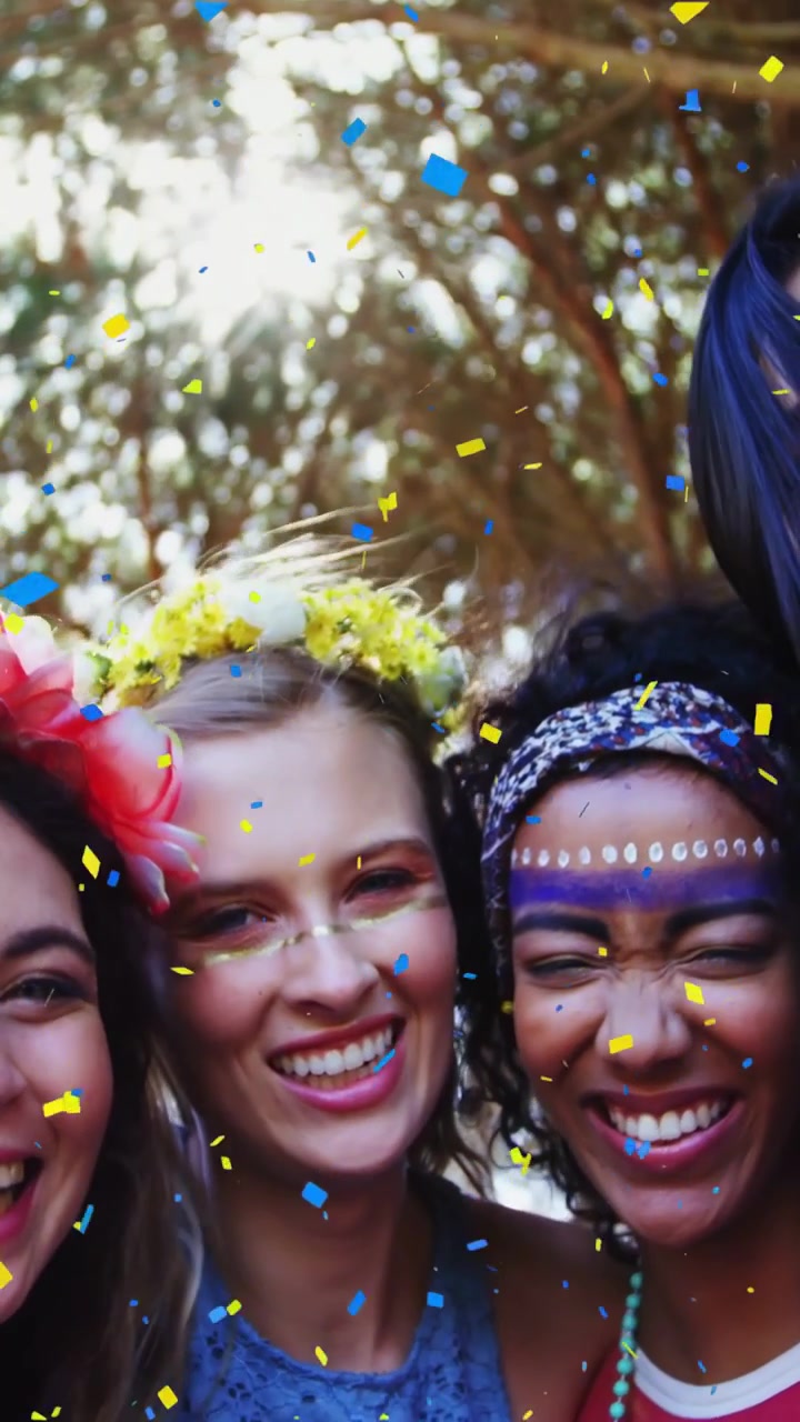 Video vertical: Confeti estallando, mujeres agrupándose, inclinándose hacia la lente, celebrando bajo un dosel.
