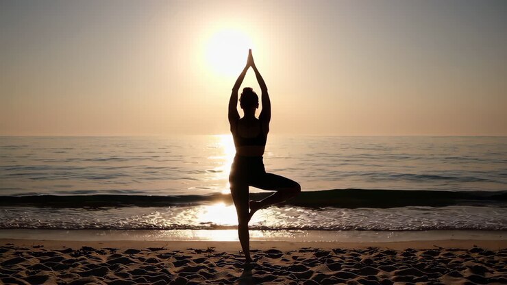 Mujer practicando yoga al amanecer en la playa
