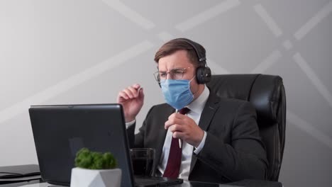 business man in medical mask and business suit talking on webcam in headphones