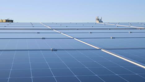 Cierre-De-La-Tecnología-De-Paneles-Solares-En-Filas-En-El-Techo-Con-Reflejo-De-Cielo-Azul,-Cámara-Lenta-De-4k