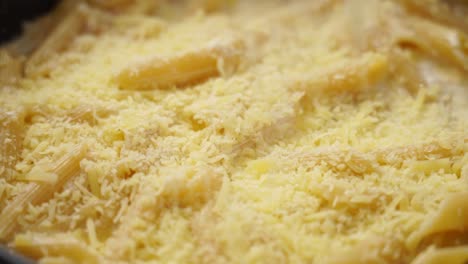 primer plano de la cocina de pasta en la sartén mientras un cocinero anónimo agrega queso