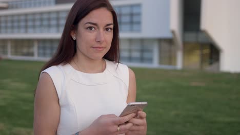 una hermosa mujer pelirroja usando un teléfono inteligente y mirando a la cámara