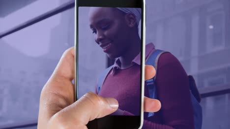 Animation-of-hand-with-smartphone-over-happy-african-american-businesswoman-using-smartphone