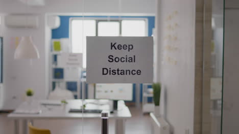 keep social distance sign on glass wall in empty office