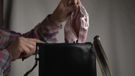 woman getting face mask out of handbag medium shot