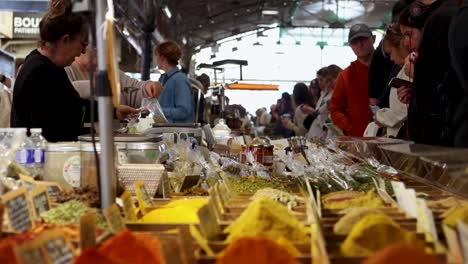 people shop at bustling market stall with colorful spices on display in antibes, france