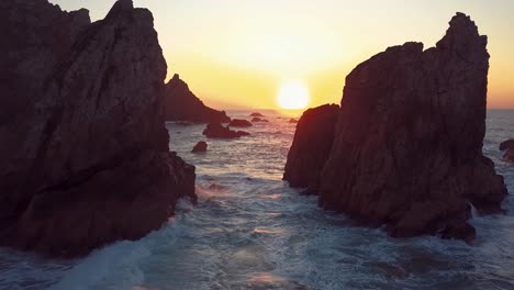 crashing waves toward the rocks in praia da ursa, sintra, portugal