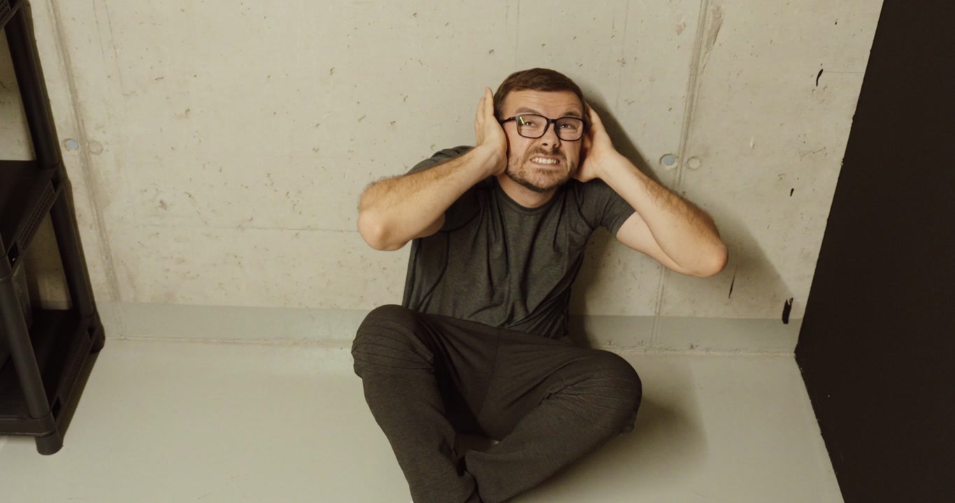 Man sitting inside a bunker or shelter while waiting during a dangerous conflict situation. Concept of civilians seeking protection from rockets or drone attacks during war and military tensions.