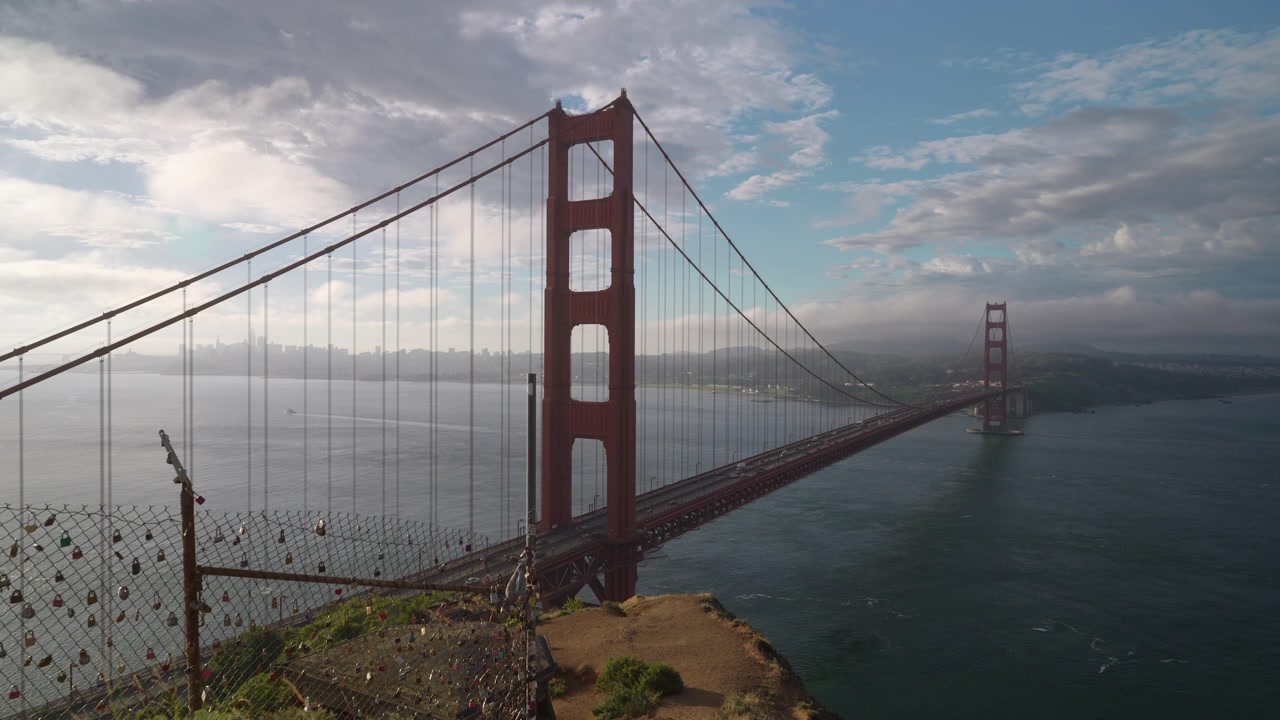 Golden Gate Bridge og hængelåse på et trådhegn, vidvinkelbillede ved solopgang