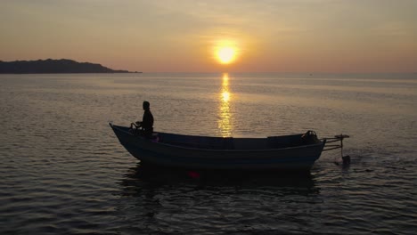 silhouette of fisherman in his boat searching for fish during golden hour