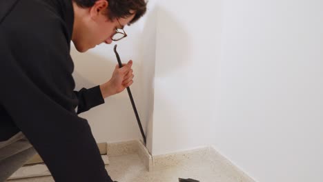 closeup on white hand removing tile with pry bar and hammer