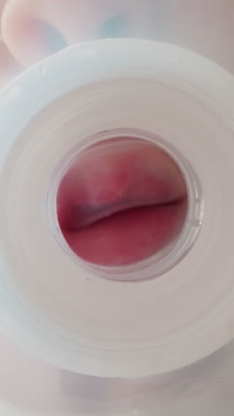 cute boy holds empty transparent bottle and sucks on white silicone nipple. thirsty child after drinking puts bottle on table and disappears macro low angle shot