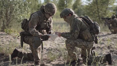 military personnel reviewing a map in the field