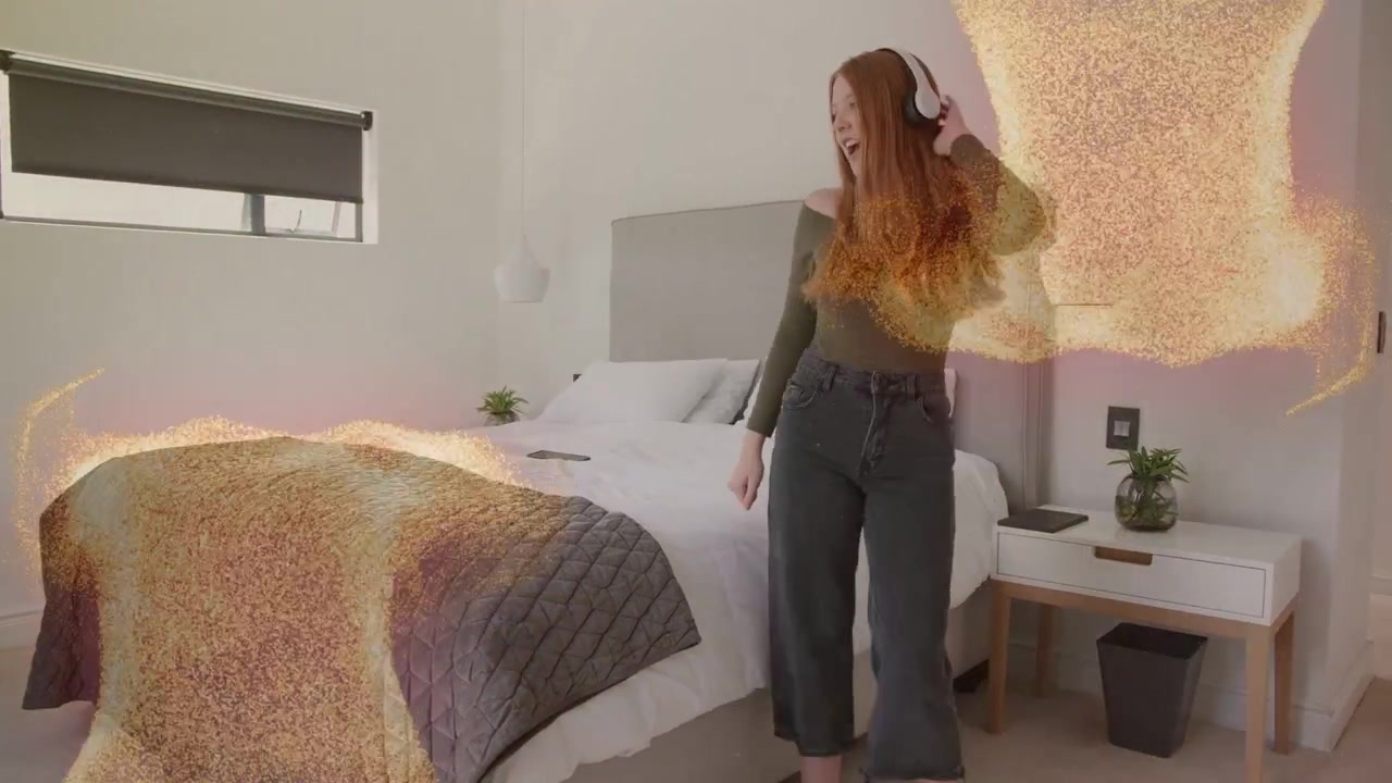 Kvinde danser ved sengen, hovedtelefoner dukker op, igangsætter gyldne partikler, mens hun lytter til musik.