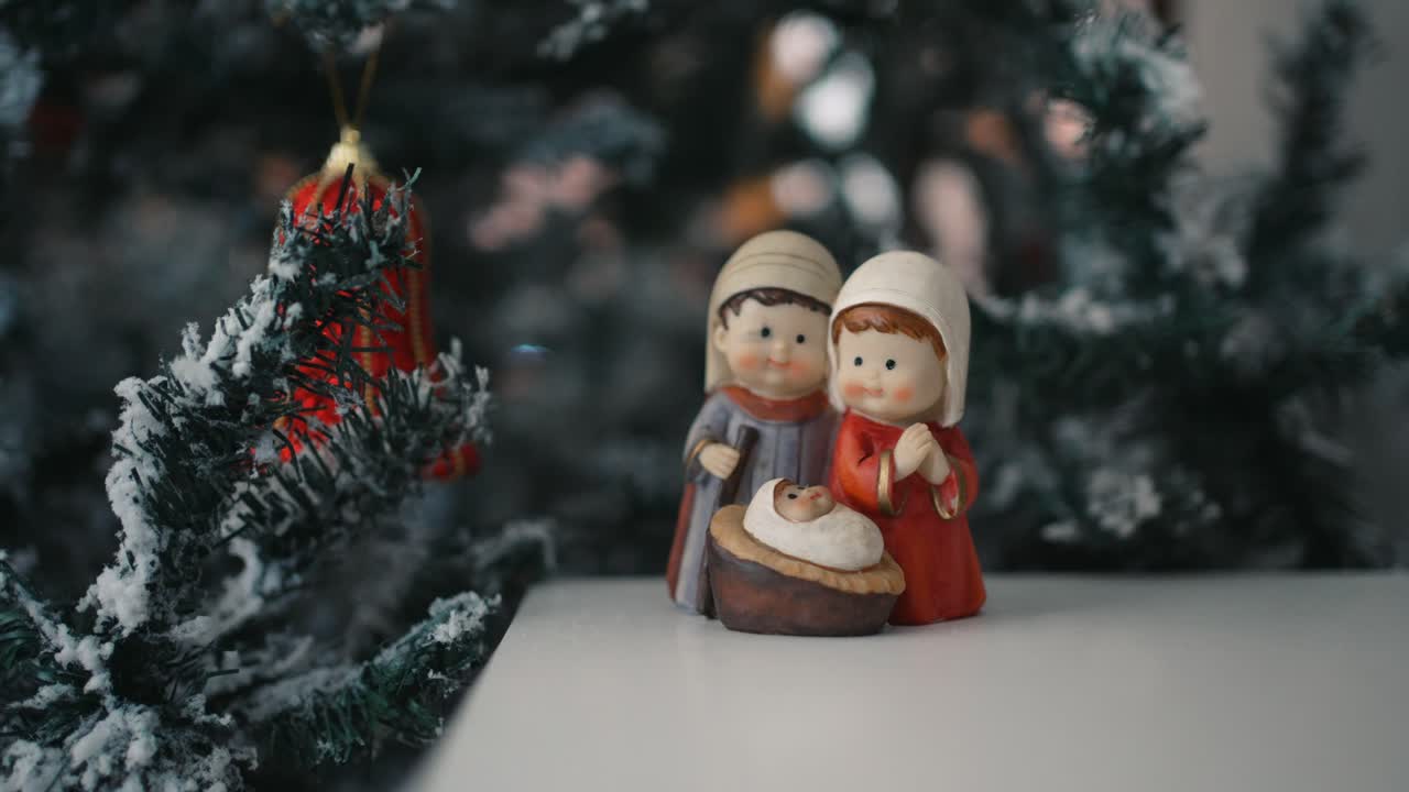 Statuine del presepe con un albero festivo sullo sfondo - primo piano con zoom indietro.
