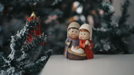 nativity figurines with festive tree backdrop - close up zoom out