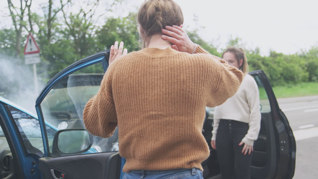 두 명의 여성 운전자가 자동차 사고 후 차에서 나온다.