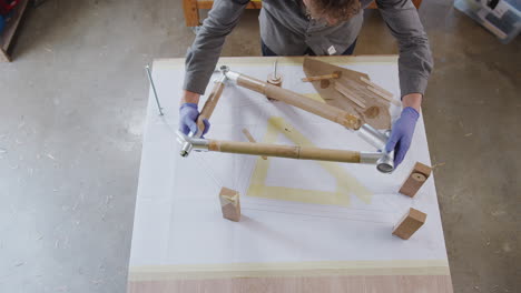 Fotografía-Cenital-De-Un-Artesano-En-Un-Taller-De-Montaje-De-Un-Cuadro-De-Bicicleta-De-Bambú-Sostenible-Construido-A-Mano.