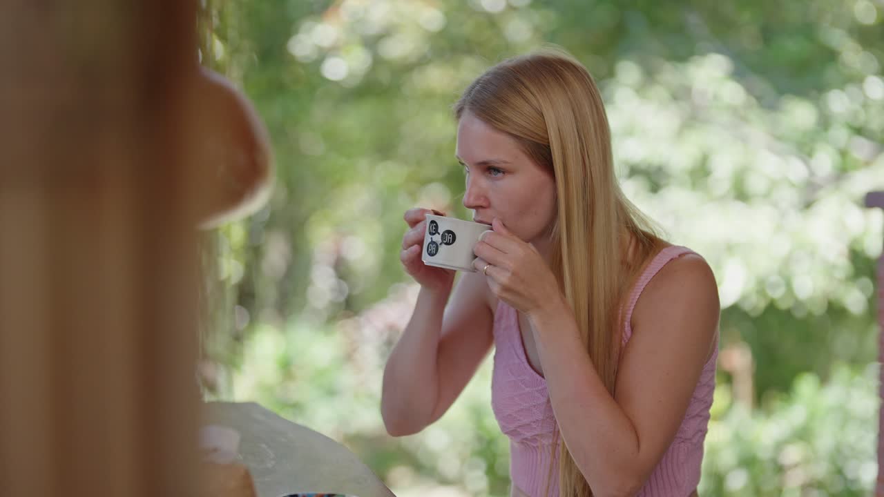 En kvinna dricker traditionellt svart kaffe medan hon njuter av palmsocker, vilket fångar en autentisk kulturell ritual och det enkla nöjet av en klassisk lokal kaffeupplevelse