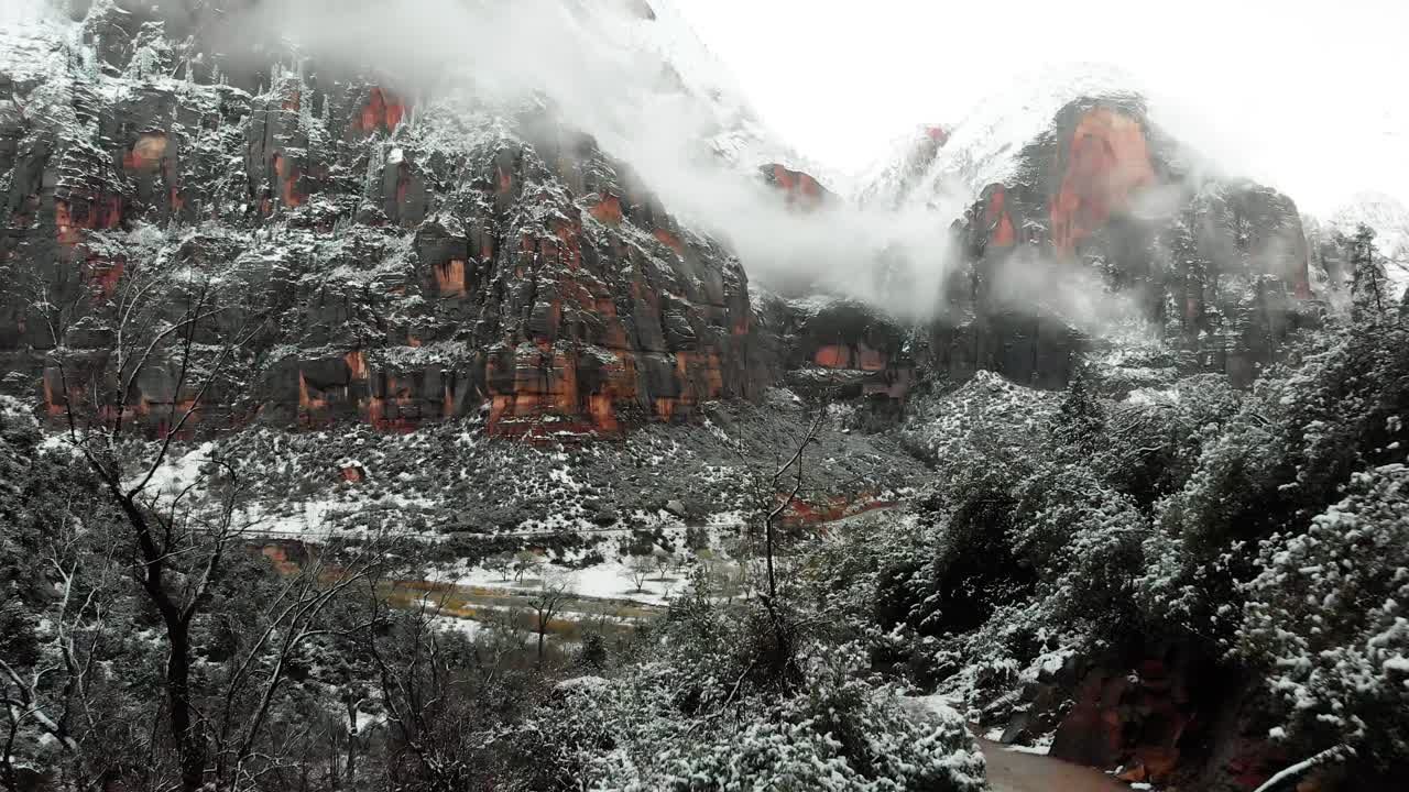 Push in shot showcasing the grey and red rock mountains in Zion National Park as the snow blankets the valley