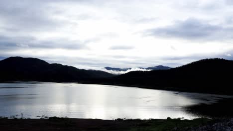 time lapse of clouded sky after thunderstorm over the mountain range and the lake in the morning with rays of sunrise