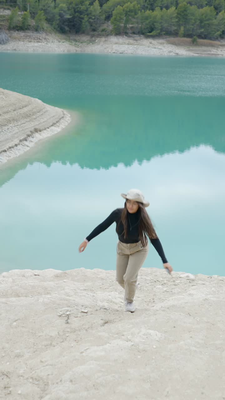 Woman walking by a beautiful turquoise lake in nature