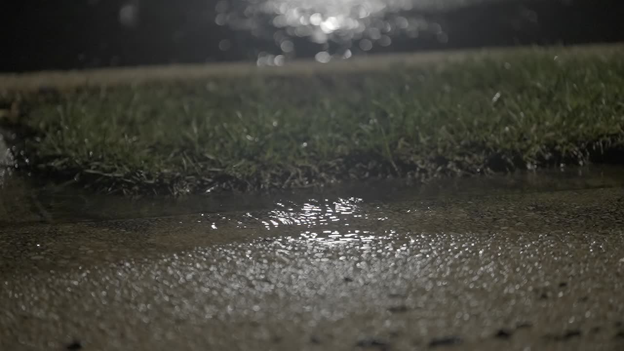 Dirty water between the sidewalk and the lawn during heavy rain