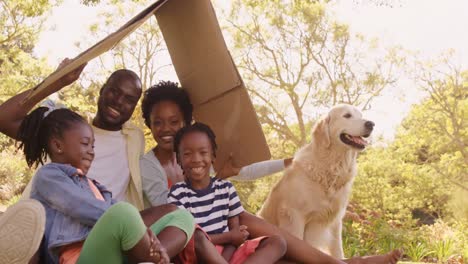 una familia linda está sentada en el parque con un perro