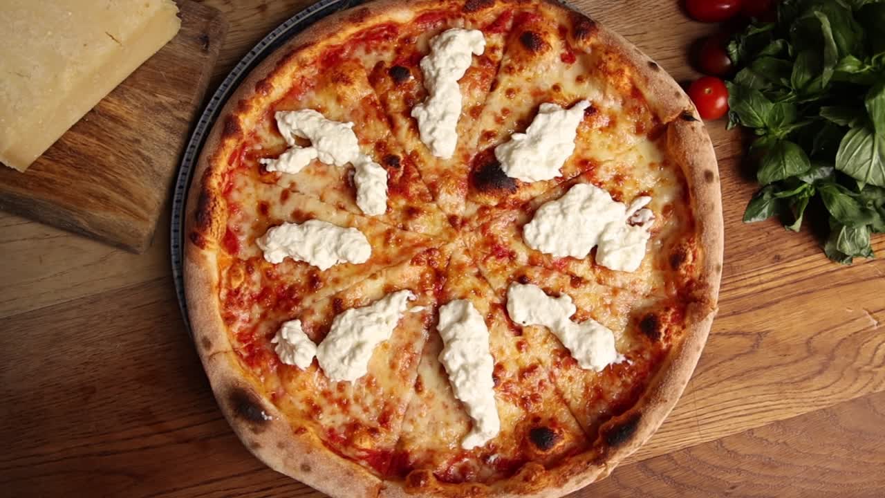 Appetitosa pizza italiana con ricotta che ruota su un tavolo di legno.