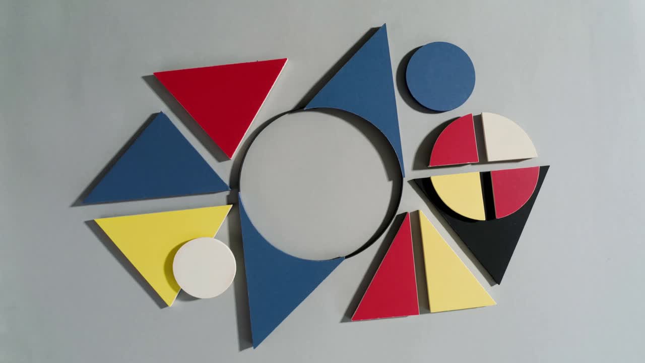 At start camera showing display of wooden geometric shapes on light grey tabletop with shadows