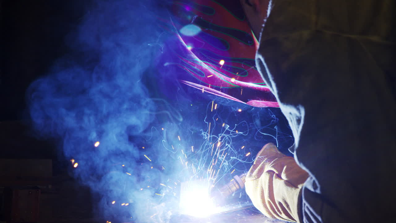 saldatore che indossa una maschera protettiva che lavora in fabbrica