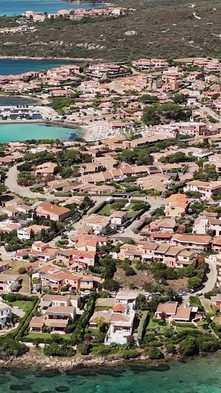 Vista di una città costiera in Sardegna con acque cristalline e spiaggia sabbiosa