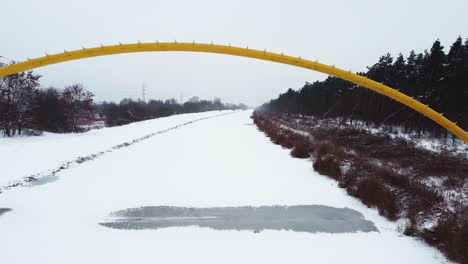 drone video of a yellow bridge on top of frozen river in forest in warsaw