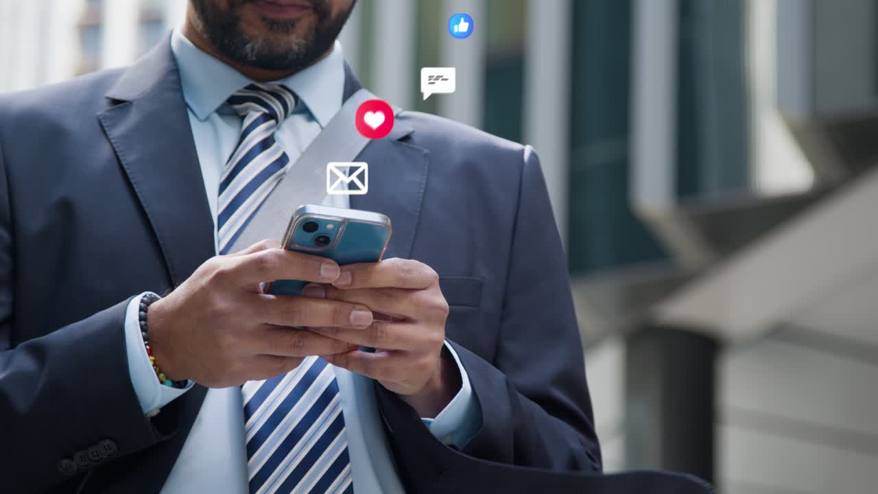 Close Up Of Businessman Standing Outside City Offices Looking At Mobile Phone With Motion Graphics Emojis Showing Multiple Messaging And Social Media Notifications